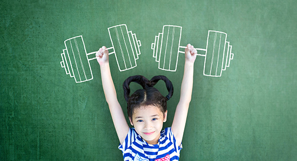 child with arms up standing in front of a chalkborad with drawn bar bells